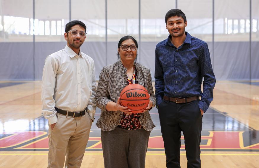 professor Ritu Chaturvedi, MDS graduate Chirag Rathi, and undergraduate student Neh Desai standing in a basketball court and posing for a group photo 