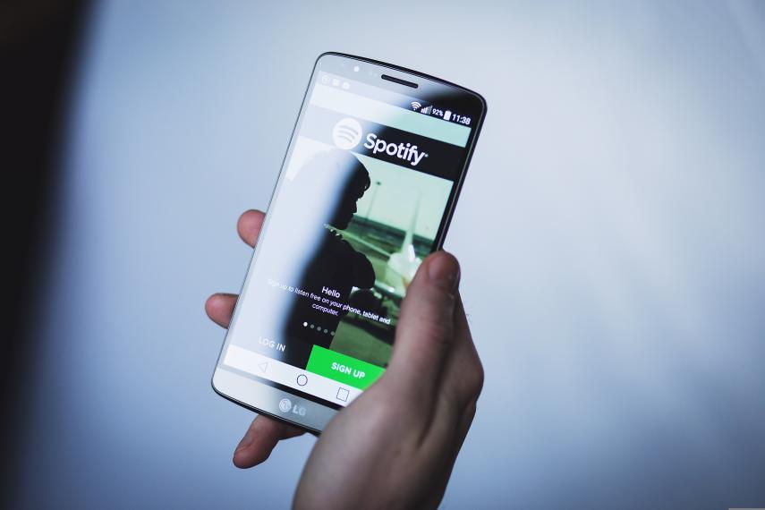 A person's hand holds a mobile phone with the Spotify app open