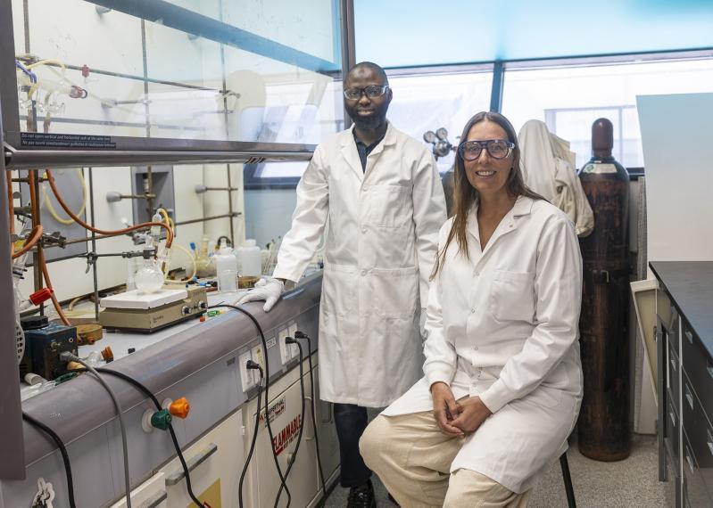 Dr. Kathryn E. Preuss and Mukaila A. Ibrahim in a lab beside lab equipment.