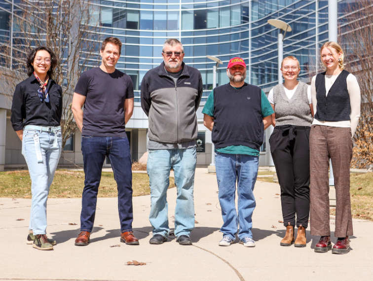 Six people standing side by side and smiling.