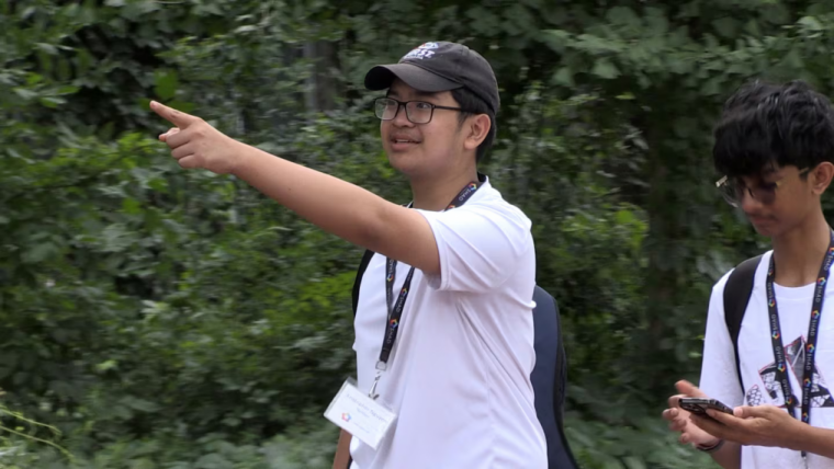 A student is walking while holding up their hand pointing.