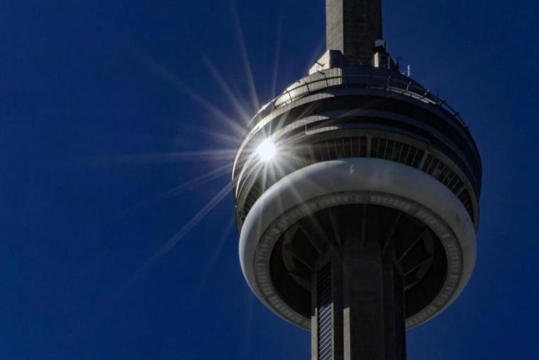 The top of the CN Tower with the sun peaking through.