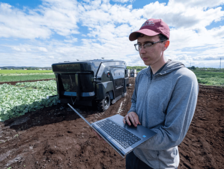 A research technician reviews data on a computer in a field