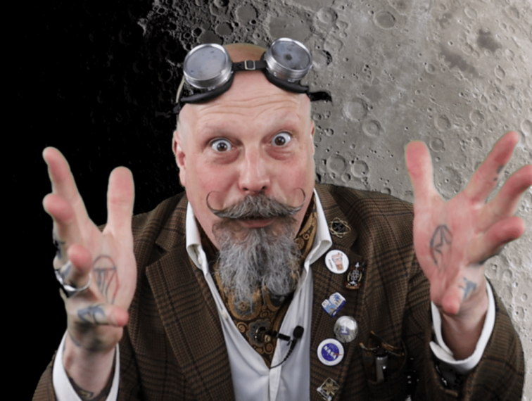 The Great Orbax gesturing with his hands to the camera.