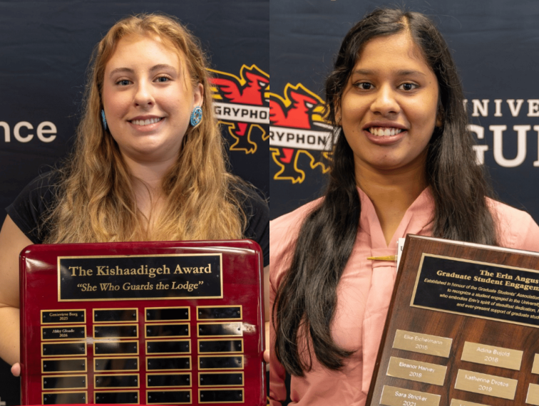 Two students holding award plaques.