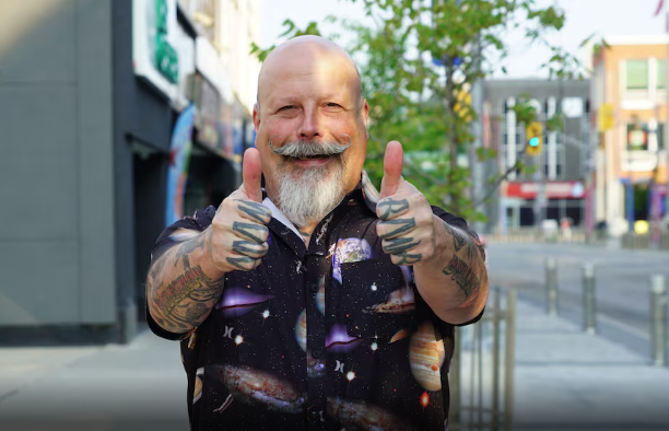 Orbax standing on a Guelph street looking at camera with thumbs up and interesting shirt.