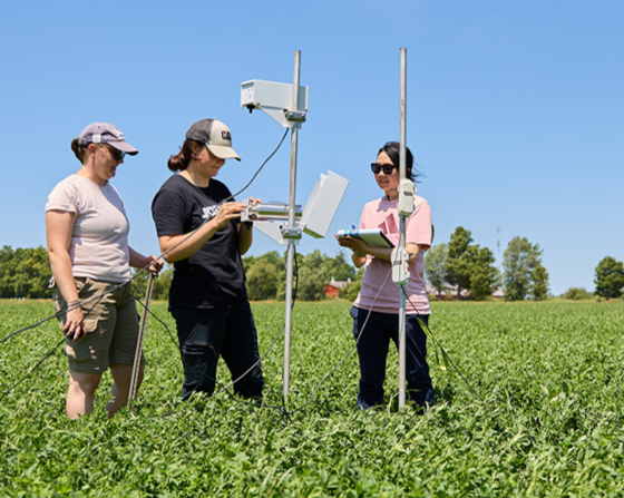Three researchers standing in a field with technology.