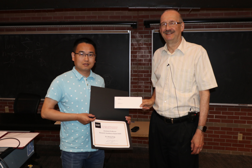 Two men standing holding an award.