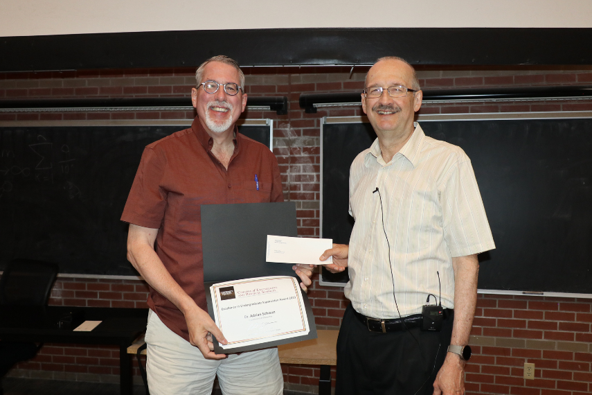 Two men standing holding an award.