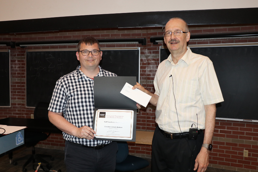 Two men holding an award.