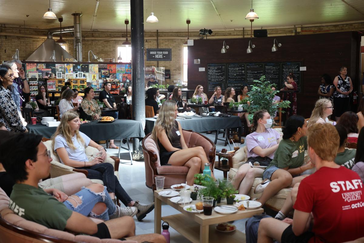 A group of people are sitting in the Bullring looking toward a speaker.