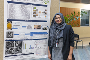 Aneela stands by their poster and smiles at camera