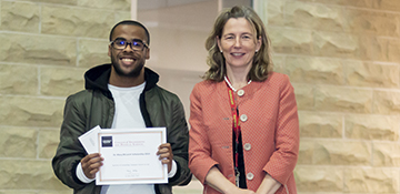 Student standing next to former dean wells holding scholarship certificate