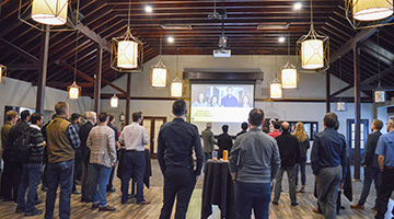 Group of people standing at CARE-AI event and watching presentation