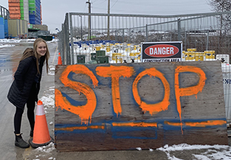 Ally Zaheer stands in front of "STOP" sign at a protest