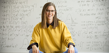 Student smiling at camera with math equations in background