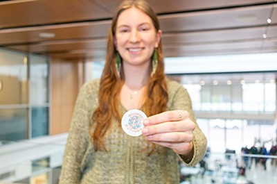 Mya Simpson out of focus holding a wellness sticker in Thorn