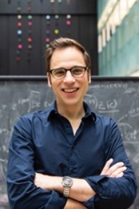 Dr. Daniel Siegel standing in front of a blackboard with equations written on it