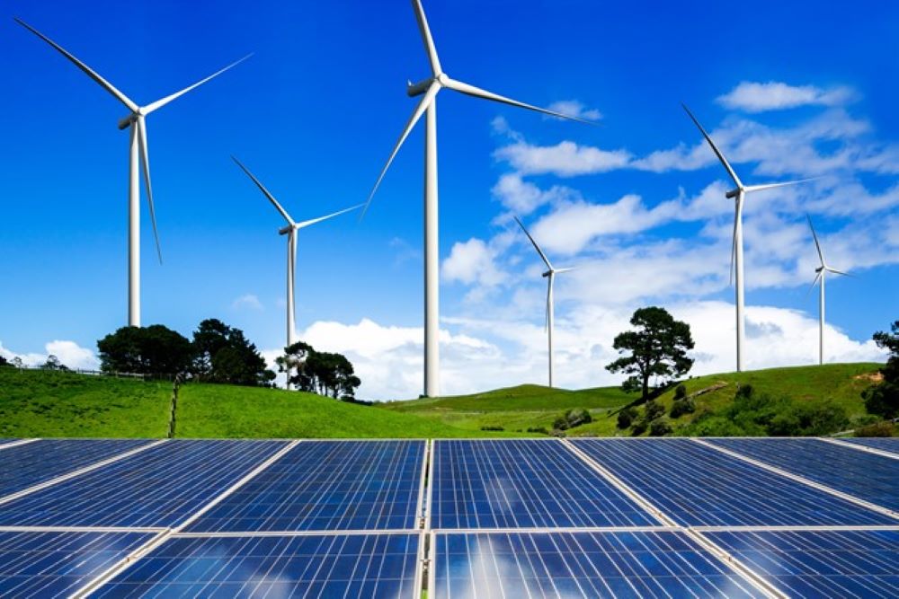 Image of wind turbines and solar panels against a blue sky.