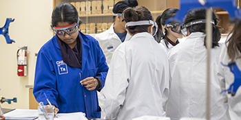 Image of graduate teaching assistant in lab with students in background
