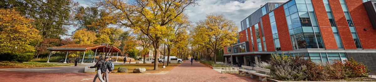 Two students walking across campus in front of the Albert A Thornborough building