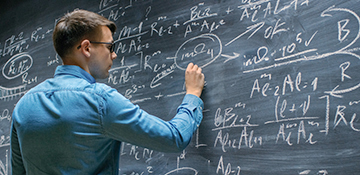 Person writing equations on chalkboard
