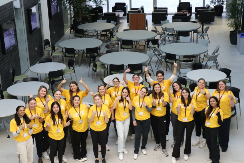 image of students smiling in Engineering building smiling at camera in yellow shirts