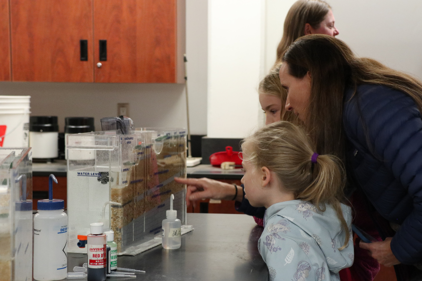 Mom and two daughters observing glass case