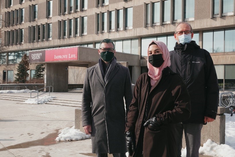 Three people standing outside of the University Centre