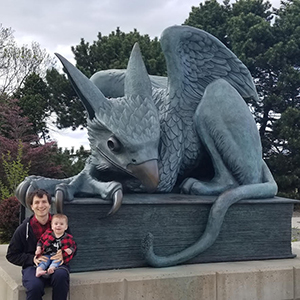 Image of Mihai and his child in front of the Gryphon statue on U of G campus