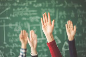 Students raising hands in classroom setting