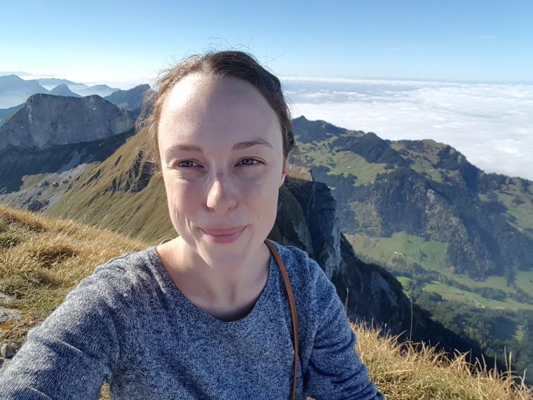 Hillary Dawkins standing on mountain with scenic view in background on sunny day