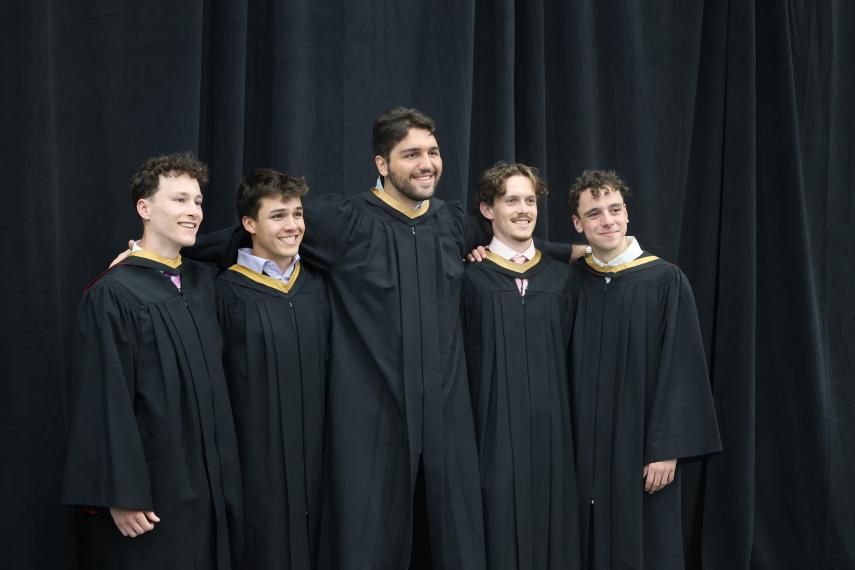 Five graduating students standing together and smiling.