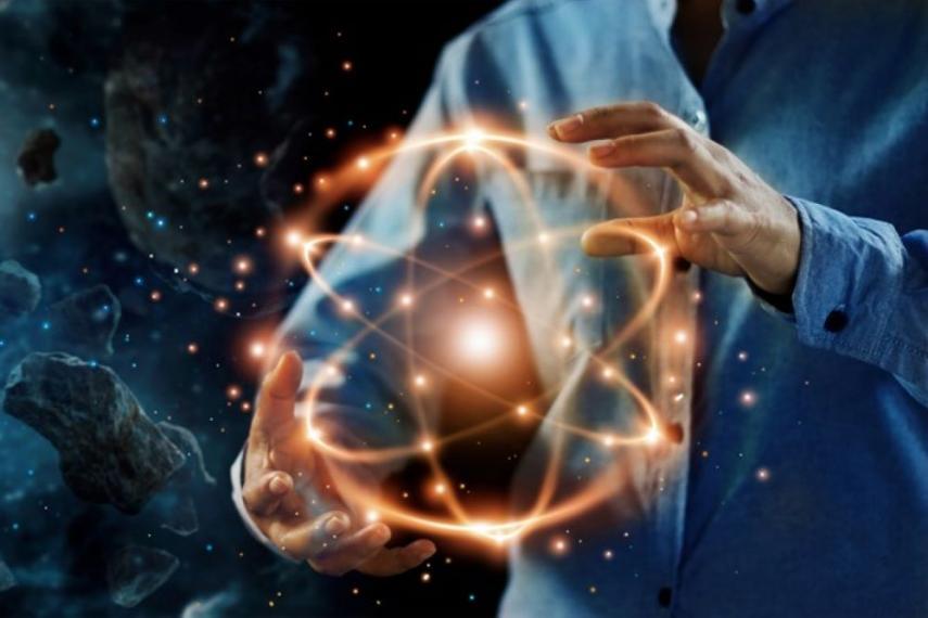 Person holding an illustration of an atom against the backdrop of space.