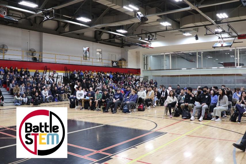 Hundreds of Students gathered for Battle STEM awards ceremony in the W.F. Mitchell Athletics Centre, Mitchell Gym, with the Battle STEM Logo graphic with a white background in the bottom left