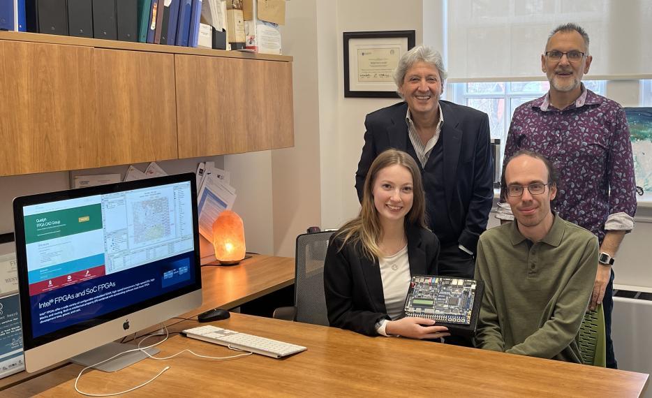 Dr. Shawki Arebi, Dr. Gary Grewal, Charlotte Barnes, and Timothy Martin pose with their digital circuit creation in an office 