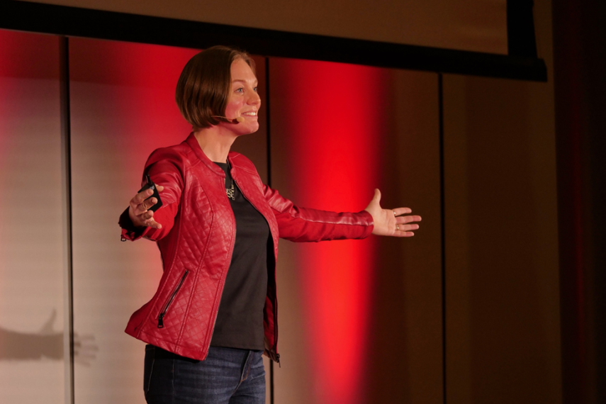 Emily Nichols holds her arms out while presenting at TedX
