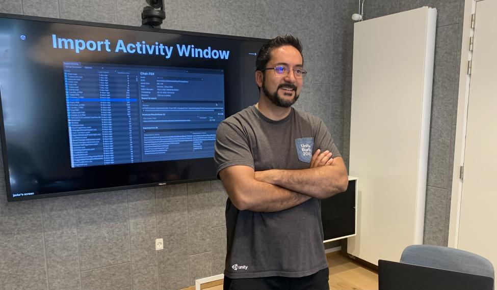 Javier Abud at work with his arms crossed while standing in front of a screen.