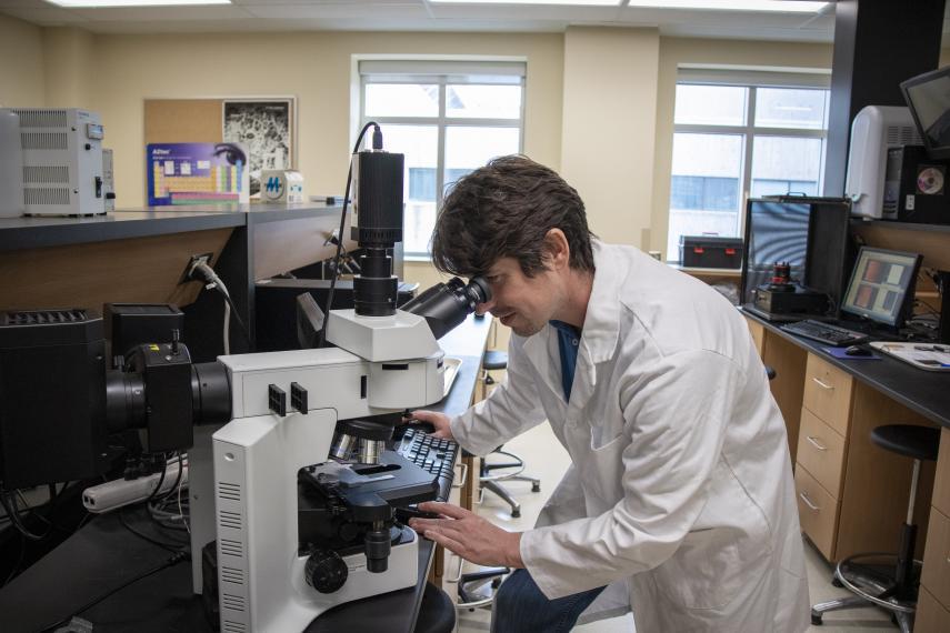 Image of Jay Leitch looking into equipment in nanoscience lab