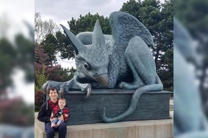 Dr. Mihai Nica and his young son sitting in front of the Gryphon statue on U of G campus.