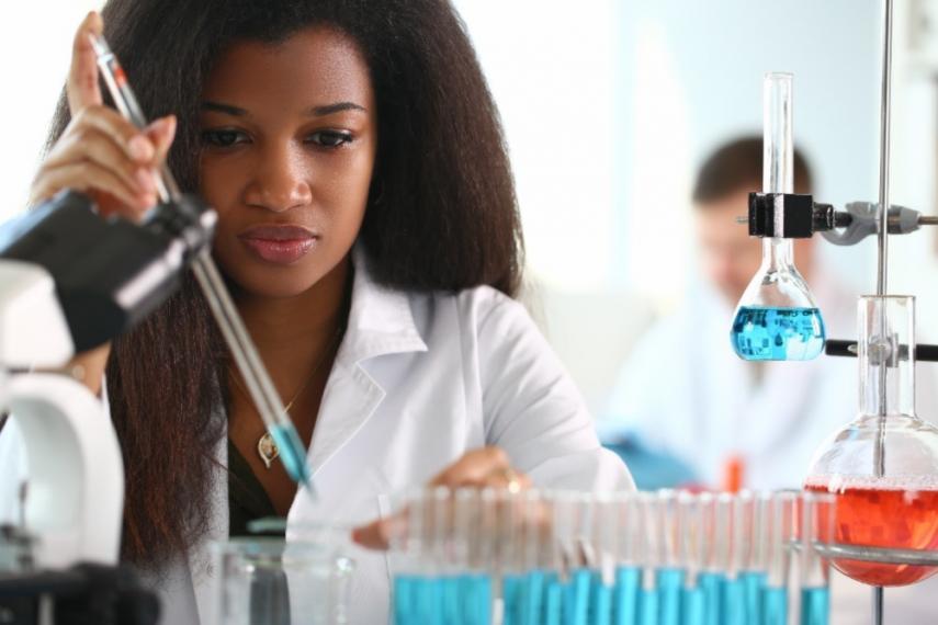 woman holding a pipette and filling beakers with a solution