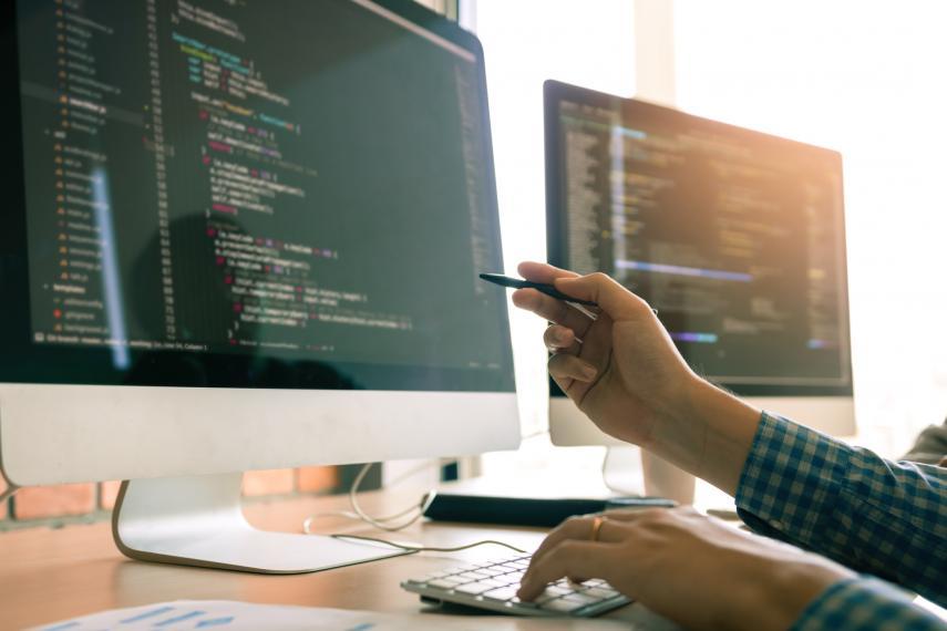 Image showing a computer screen with the hands of someone working on the computer.