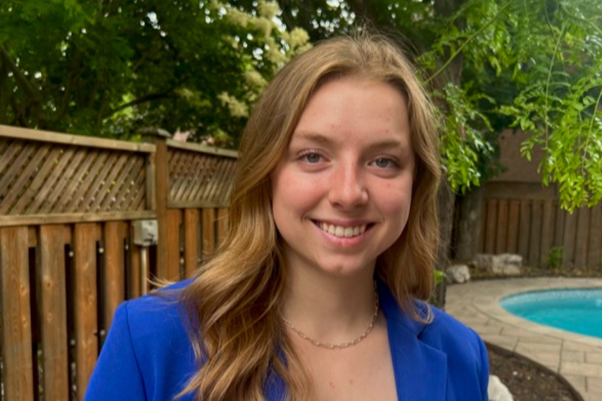 girl in bright blue blazer smiles at camera with pool in background