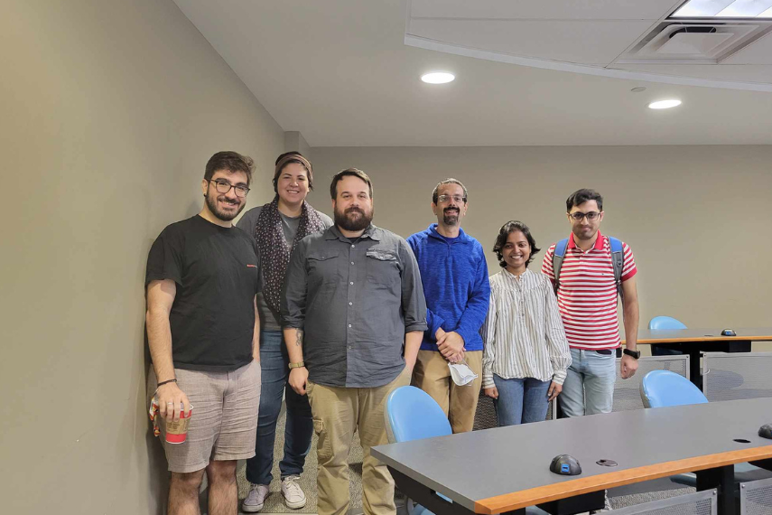 Group of people standing on stairs of computing classroom smiling at camera.