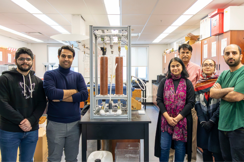 Group of researchers posing in lab with heat exchanger.
