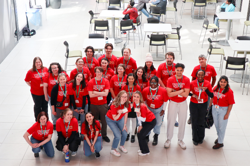 Group of volunteers posing in red shirts in Engineering Atrium.