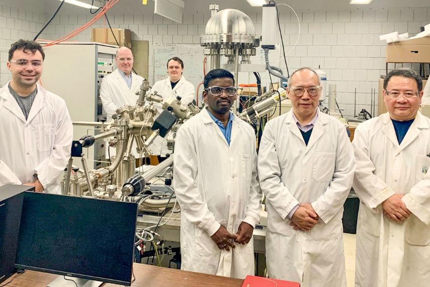 Group of scientists posing in lab with their work. 