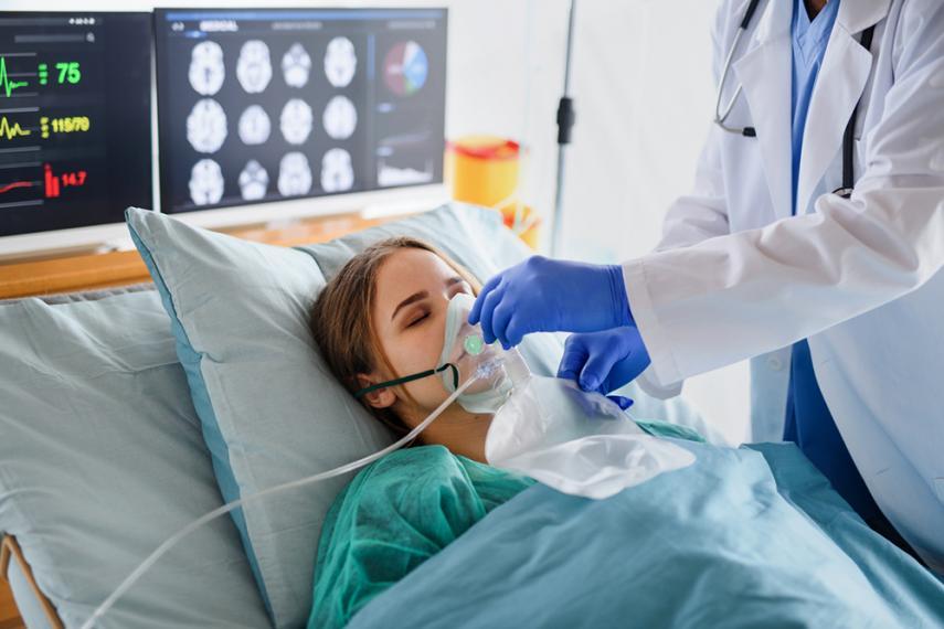 Person lying in hospital bed with oxygen mask