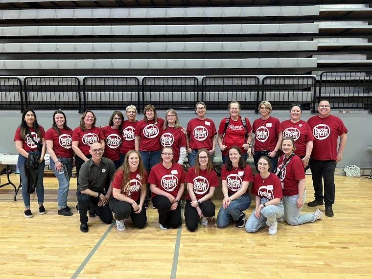 Large group of Battle STEM volunteers smiling at camera and wearing red volunteer shirts