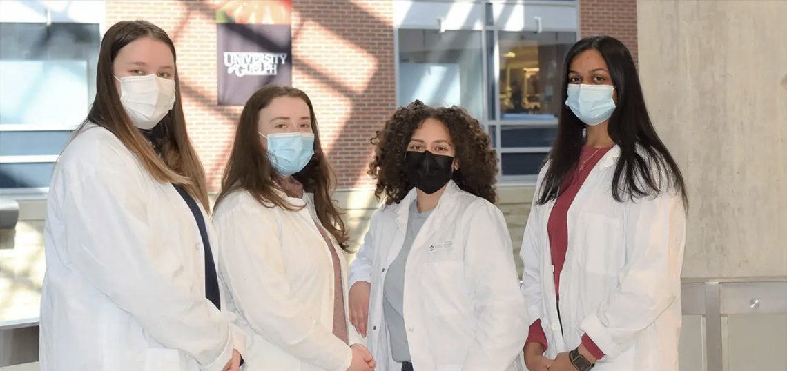 image of four women in white lab coats with mask looking at the camera